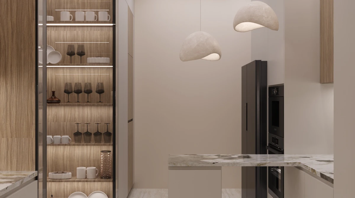 مطبخ حديث أنيق مع تصميم بسيط يشمل أسطح رخامية وخزائن بيضاء، بالإضافة إلى إضاءة جذابة وأرفف خشبية تعرض الأواني الزجاجية والسيراميكية.