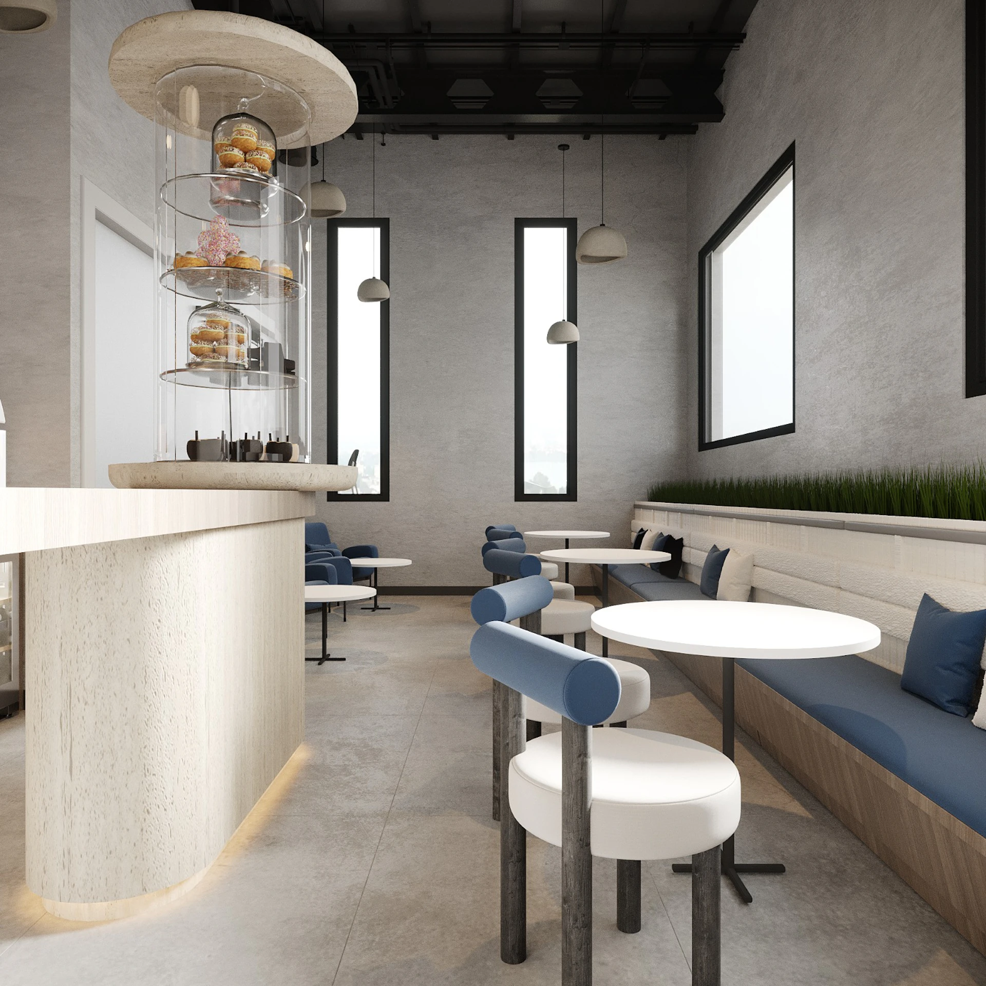 A modern, minimalist café interior featuring a sleek white and blue color scheme, with round tables, cushioned seating against the walls, and a tall central display tower showcasing assorted pastries, accented by large windows allowing natural light to flood the space.