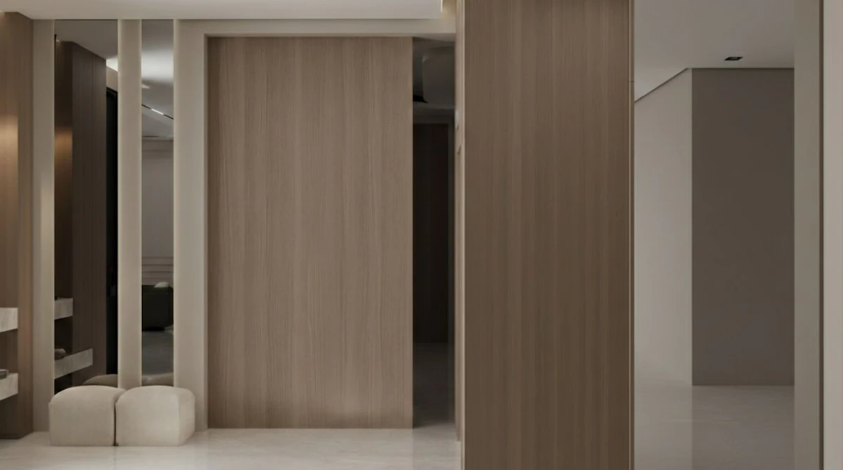A modern, minimalist hallway features smooth, beige walls with wooden paneling, sleek mirrors, and a polished, light marble floor, creating a spacious and elegant interior design.