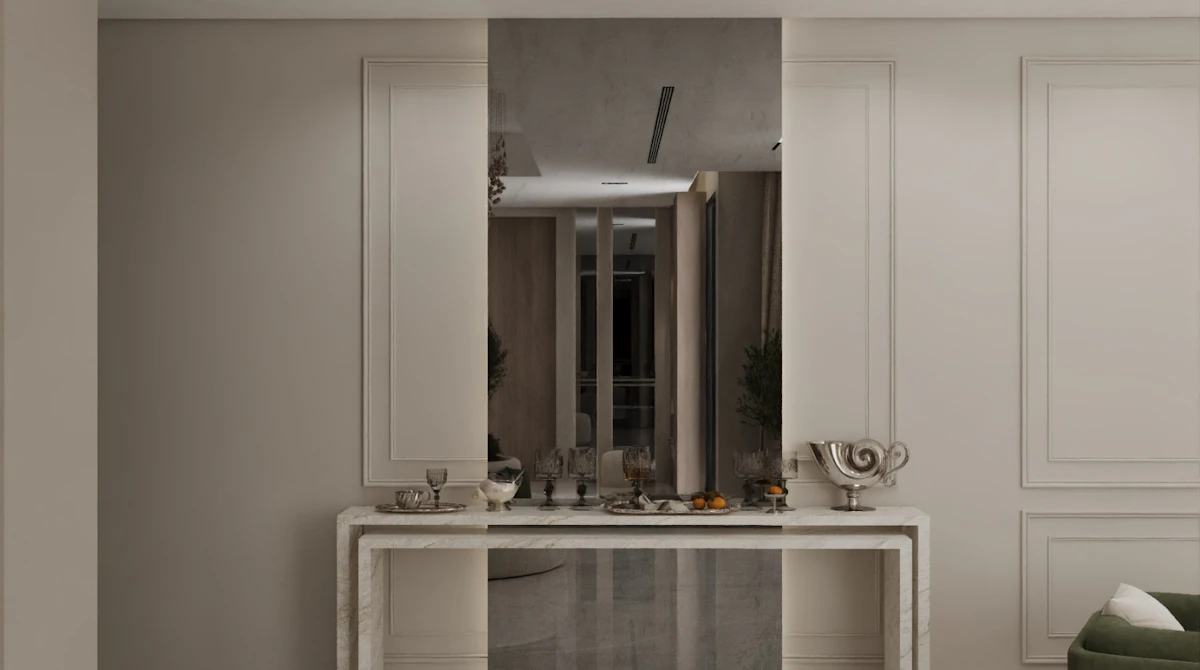 A modern interior features a sleek marble console table adorned with decorative items, set against a mirrored wall panel, framed by elegant paneling and soft lighting.