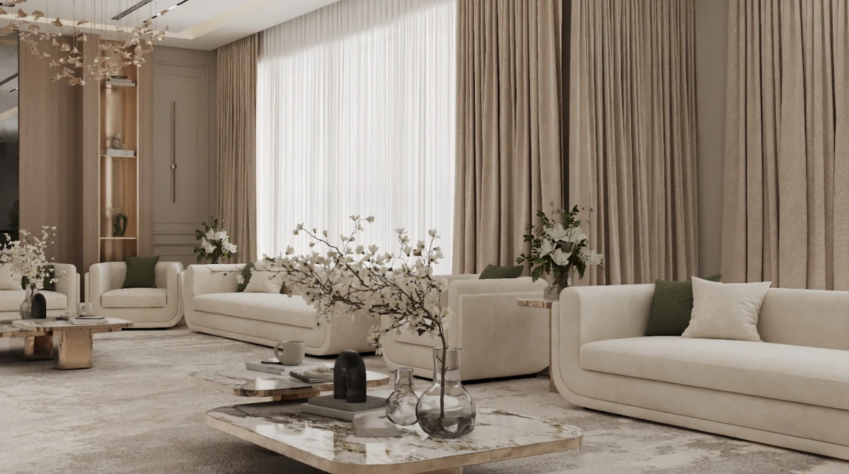 A luxurious and spacious living room features cream-colored sofas adorned with green cushions, a large marble coffee table with decorative glass vases, and elegant floor-to-ceiling curtains, illuminated by soft natural light filtering through large windows.